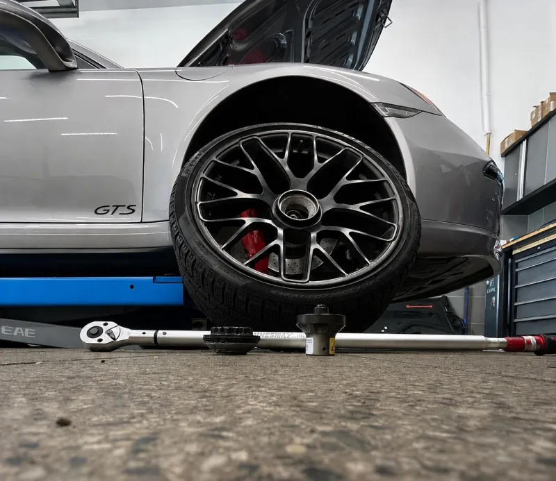 Kolo Porsche GTS opřené o vůz vedle momentového klíče v pneuservisu Brabenec